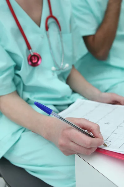 Medic in scrubs checking a chart — Stock Photo, Image