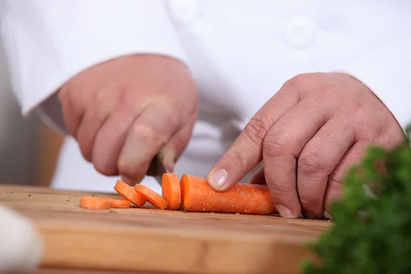 Fechar-se de um cozinheiro cenouras de redução — Fotografia de Stock