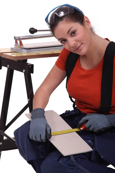 Una donna che misura una piastrella prima di tagliarla . — Foto Stock