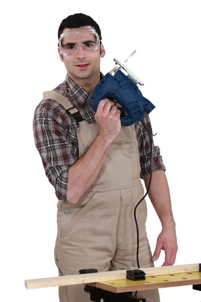 Man wearing safety goggles whilst holding band-saw — Stock Photo, Image