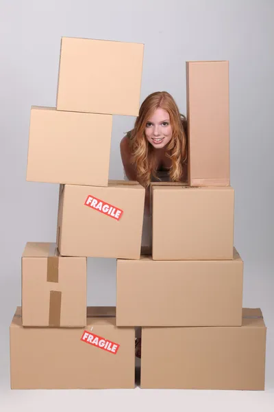 Mujer parada junto a un montón de cajas de cartón —  Fotos de Stock