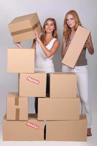 Unga kvinnor stapla lådor — Stockfoto
