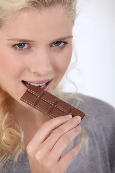 Frau beißt in ein Stück Schokolade — Stockfoto