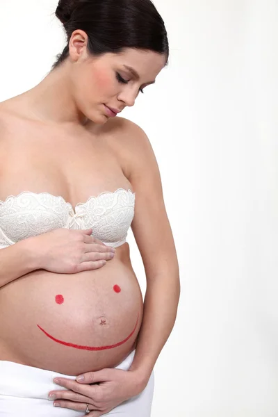 En gravid kvinna med en smiley målade på magen. — Stockfoto