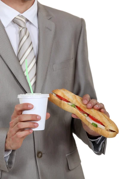 Бизнесмен с бутербродом и безалкогольным напитком — стоковое фото