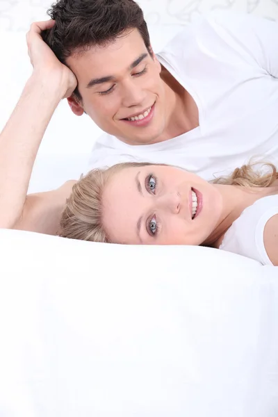Mladý pár v bílém na bílé posteli — Stock fotografie