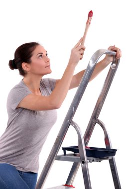 Woman with paint brush climbing step ladder clipart
