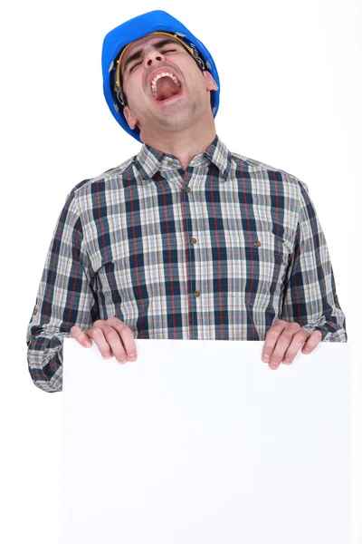 Screaming builder with a board left blank for your message — Stock Photo, Image