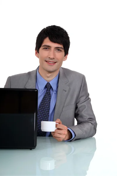 Businessman sat at desk drinking an espresso — Stock Photo, Image