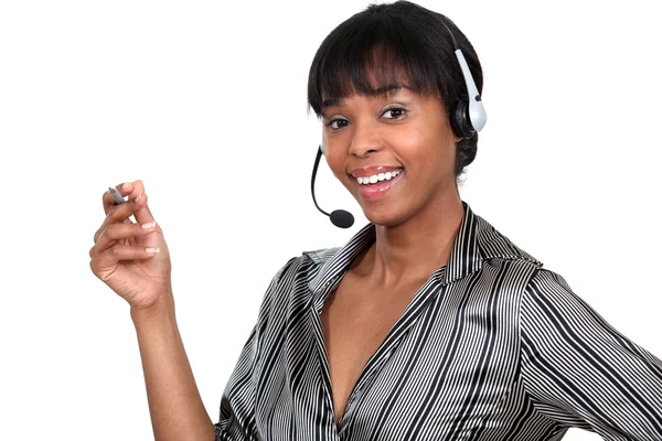 Mulher usando um fone de ouvido telefone e segurando uma caneta — Fotografia de Stock