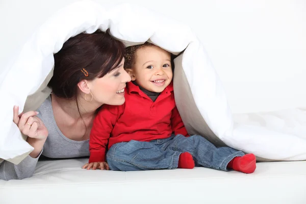 Mãe e filho brincando debaixo do cobertor — Fotografia de Stock