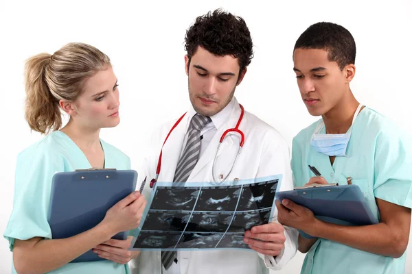 Ein Arzt und seine Assistenten bei der Untersuchung einer Röntgenaufnahme. — Stockfoto