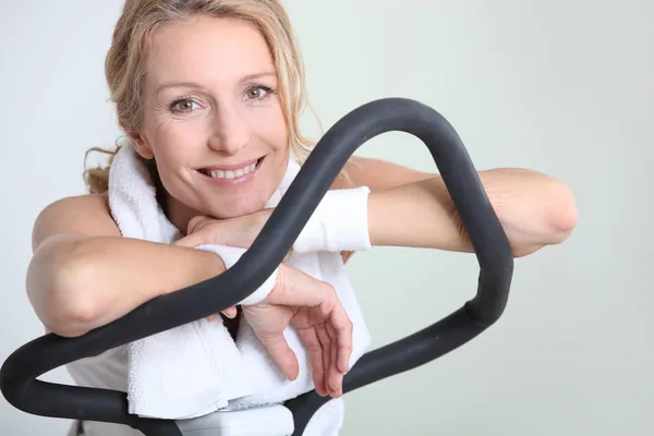 Mulher descansando por um momento em uma máquina de exercício — Fotografia de Stock