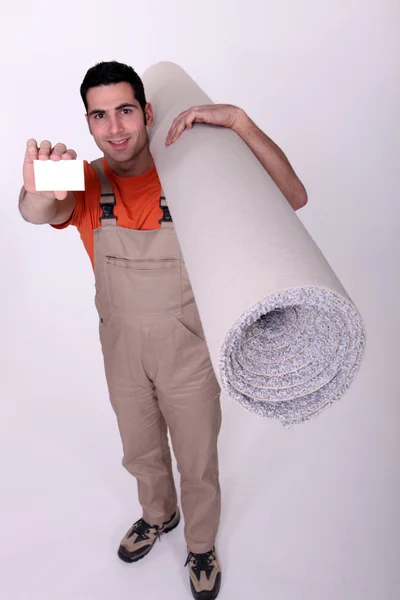 Man with a roll of carpet and a blank business card — Stok fotoğraf