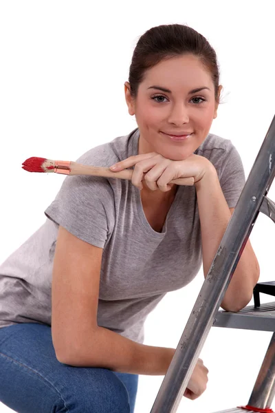 Mulher com pincel de pintura apoiada em uma escada — Fotografia de Stock