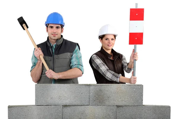 Craftsman and craftswoman standing behind a stone block wall — Stock Photo, Image