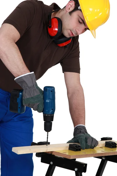 Trabalhador perfurando um buraco em uma prancha de madeira — Fotografia de Stock