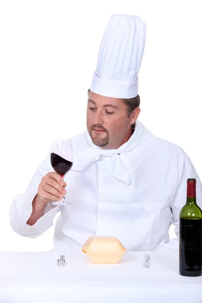 Chef com um copo de vinho tinto e caixa de junk food — Fotografia de Stock