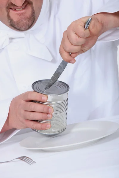 Chef tratando de abrir una lata con un cuchillo — Foto de Stock