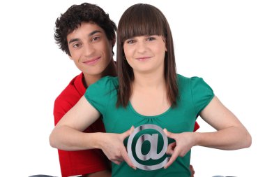 Two teenagers embracing and holding an at sign clipart