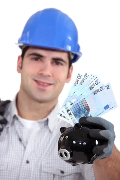 Retrato de jovem capataz segurando contas e porquinho — Fotografia de Stock