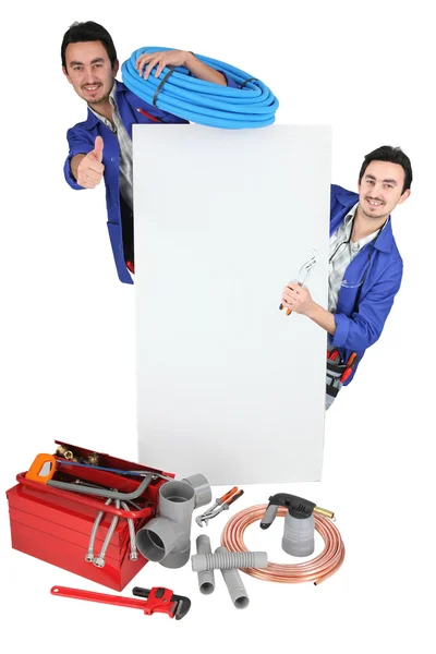 Tradesman posando com suas ferramentas e um sinal em branco — Fotografia de Stock