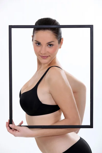 Brunette in bra holding picture frame — Stock Photo, Image