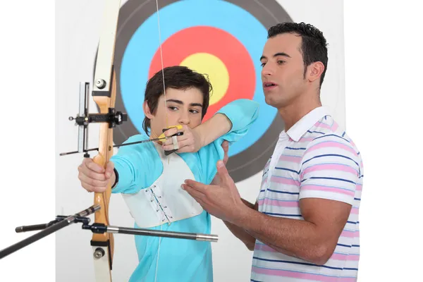 A father teaching his son how to shoot a bow. — Stock Photo, Image