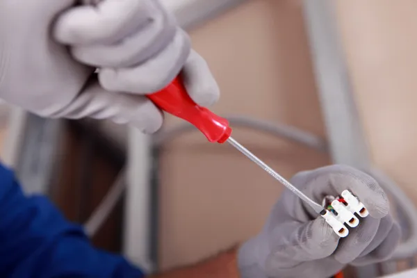 Close up of a small screwdriver being used with an electrical junction box — Stock Photo, Image