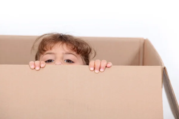 Lilla flickan gömmer sig i en kartong — Stockfoto