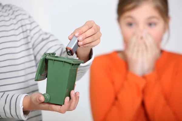 Zbliżenie chłopca oddanie baterii w miniaturze bin, ku przerażeniu jego siostra — Zdjęcie stockowe