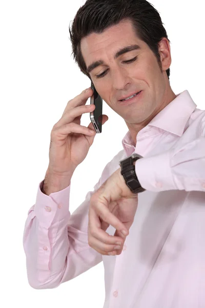 Empresario en el teléfono consultando su reloj — Foto de Stock