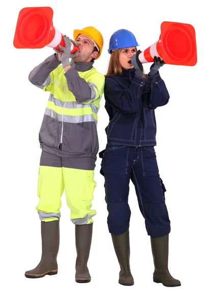A team of tradespeople yelling into pylons — Stock Photo, Image