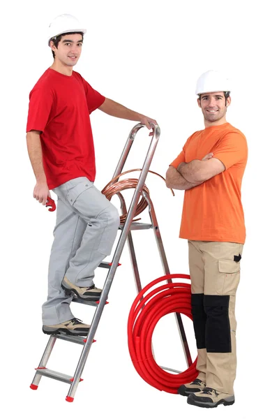 Deux plombiers se tenaient avec échelle et tuyau de cuivre — Photo