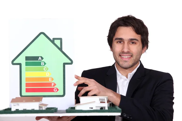 Arquitecto sosteniendo casa modelo y tarjeta de calificación energética — Foto de Stock