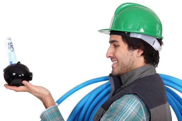 Electrician holding piggy-bank — Stock Photo, Image