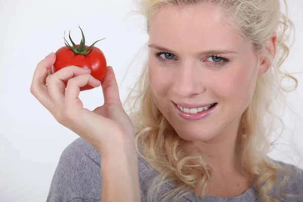 Una mujer rubia sosteniendo un tomate en su mano — Foto de Stock