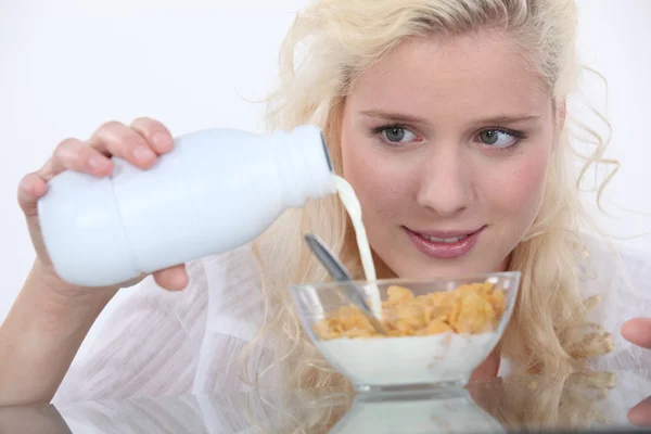 Frau gießt Milch in Müslischale — Stockfoto