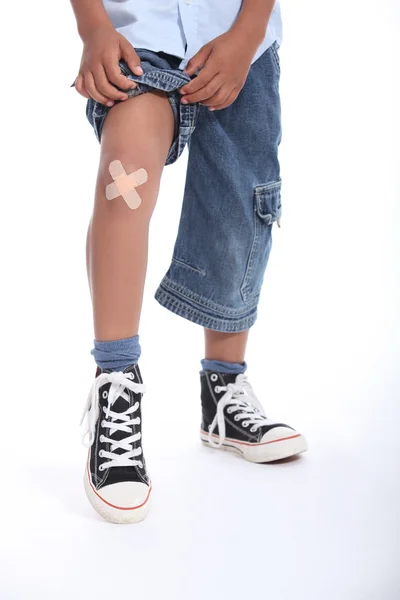 Little boy with plaster on his knee — Stock Photo, Image