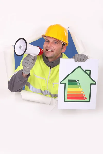 Craftsman talking through a megaphone and holding an energy consumption label — Stock Photo, Image