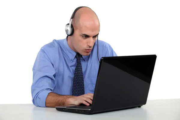 Affärsman bär hörlurar att skriva på laptop — Stockfoto