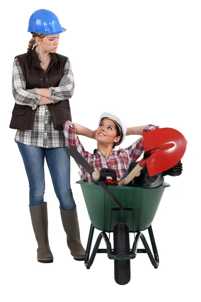 Craftswoman accusing her lazy colleague for sitting in a wheelbarrow — Stock Photo, Image