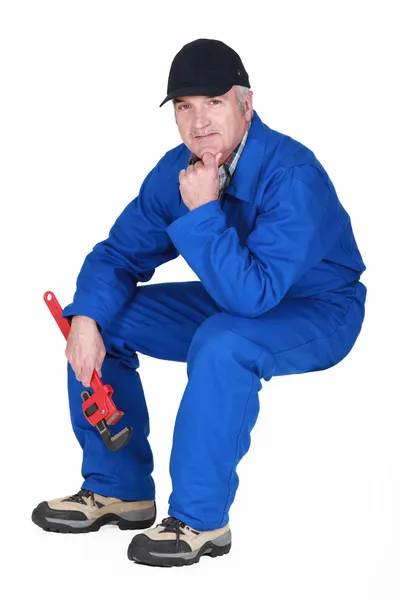 Senior plumber sat holding wrench — Stock Photo, Image