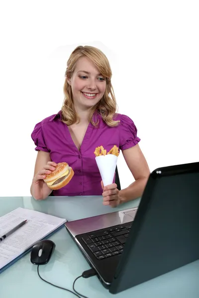 Eine Geschäftsfrau mit Junk Food in ihrem Büro. — Stockfoto