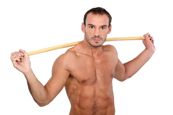 Hombre de pecho desnudo mostrando con palo sobre fondo blanco — Foto de Stock