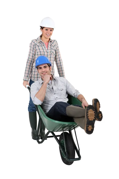 Woman pushing a man in a wheelbarrow — Stock Photo, Image