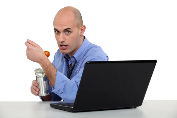 Businessman eating canned food at his desk — Stock Photo, Image