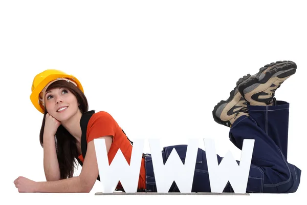 Craftswoman lying on the floor with face resting on fist and www symbol — Stock Photo, Image