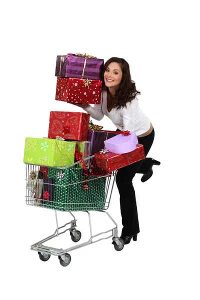 Woman pushing trolley full of presents — Stock Photo, Image