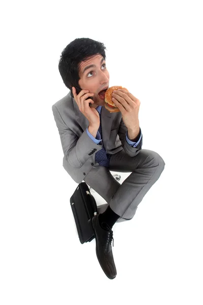 Businessman on the phone eating hamburger — Stock Photo, Image